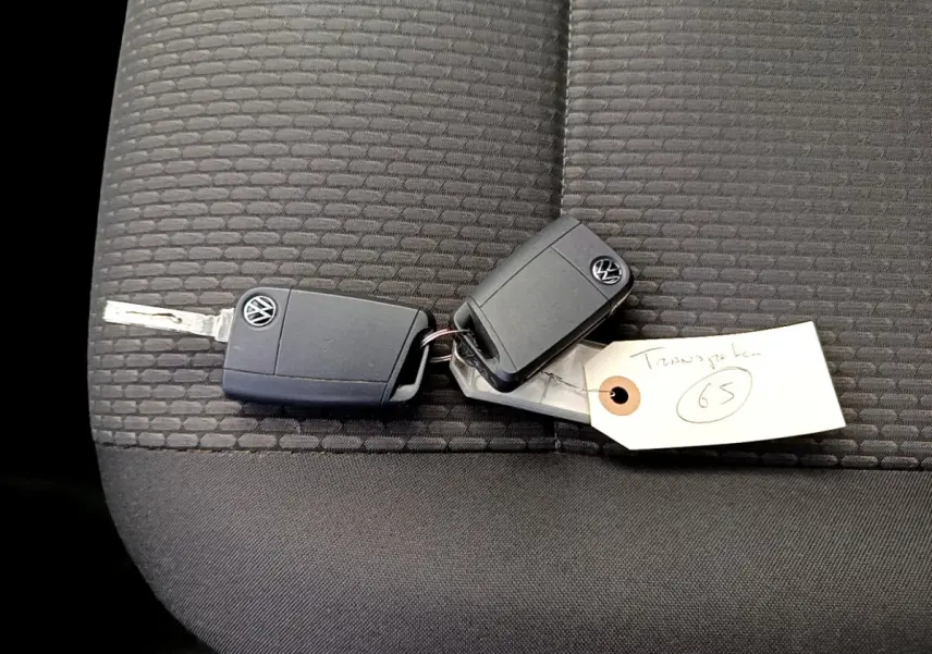 Clé Volkswagen posée sur un siège tissu gris foncé à motifs, intérieur du Transporter 2.0 TDi 150 DSG7 Business.