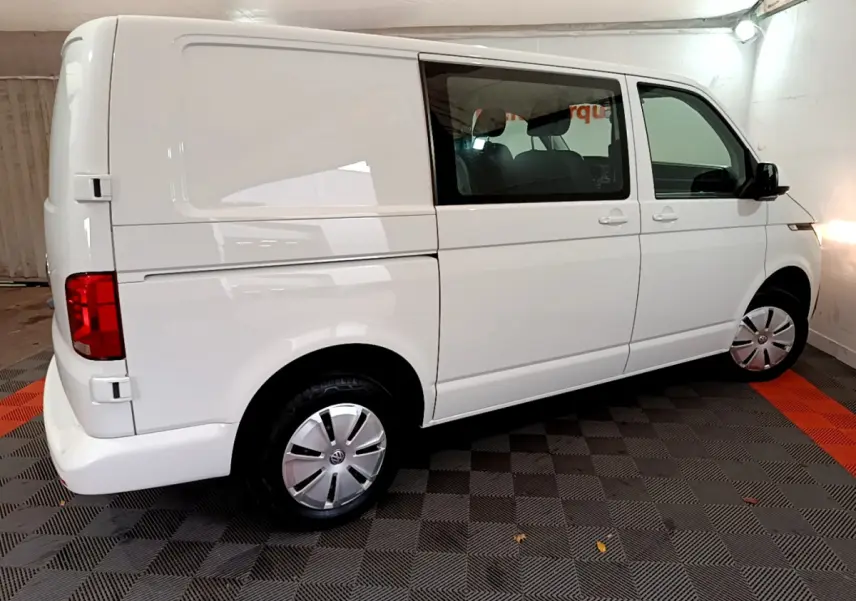 Vue 3/4 arrière droite d'un Volkswagen Transporter blanc avec vitres teintées et jantes acier en intérieur.