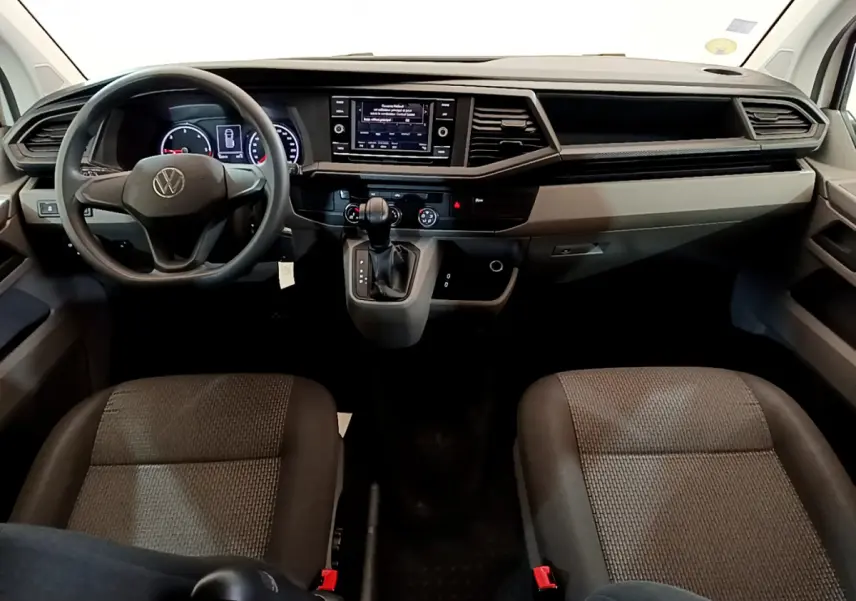 Intérieur avant du Volkswagen Transporter blanc 2021, tableau de bord moderne avec écran tactile et volant multifonction.