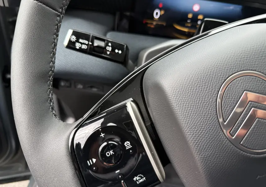 Gros plan sur le volant gris du Citroën C5 Aircross II Hybrid avec commandes intégrées et logo central visible.