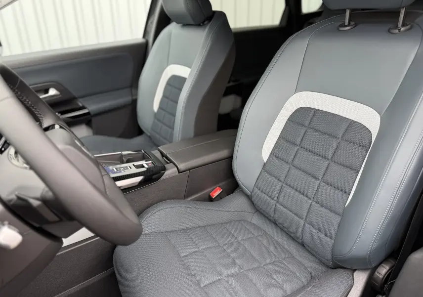 Vue rapprochée des sièges avant gris et noirs du Citroën C5 Aircross II Hybrid 2026, avec console centrale visible.