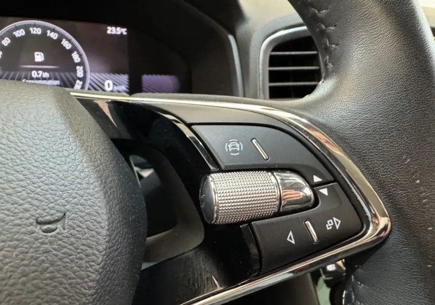Gros plan sur les commandes multifonctions à droite du volant cuir du Skoda Karoq 2024, affichage digital en arrière-plan.