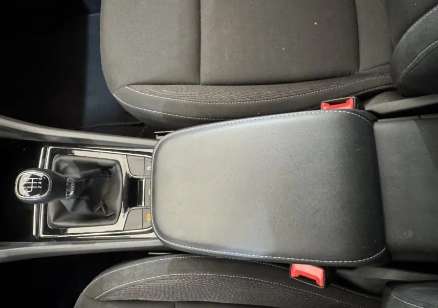 Vue rapprochée de l’accoudoir central noir et levier de vitesses manuel dans l’habitacle du Skoda Karoq blanc 2024.