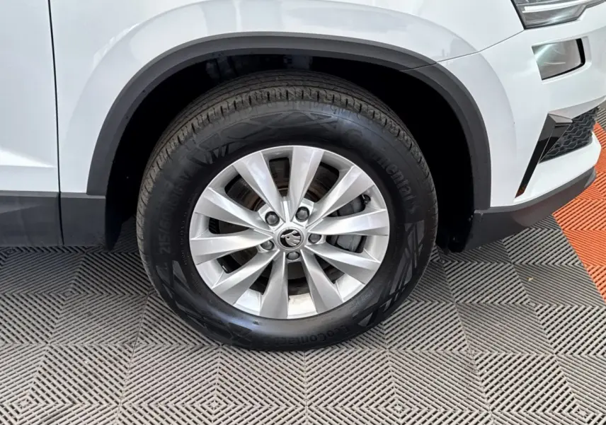 Gros plan sur la roue avant droite d’un SUV SKODA KAROQ blanc, avec jante alliage et pneu Continental.