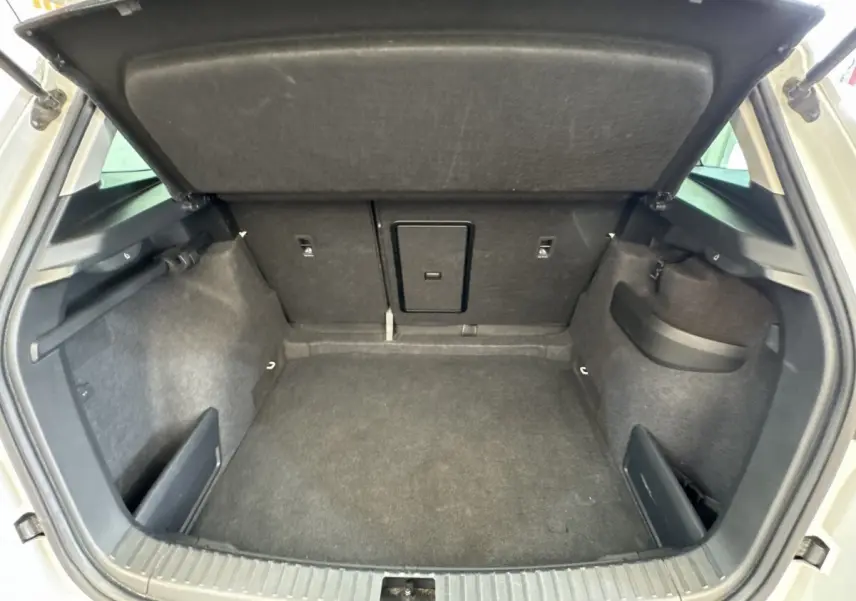 Vue intérieure du coffre ouvert du Skoda Karoq blanc 2024, montrant un espace de rangement propre et spacieux.