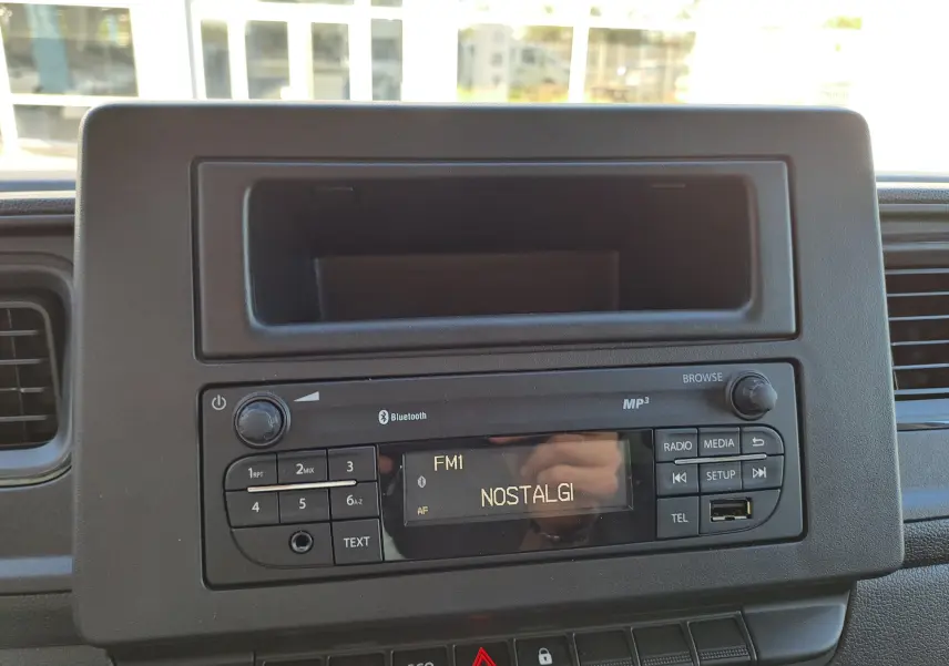 Vue rapprochée de la radio Bluetooth du tableau de bord du Nissan Interstar blanc, version 2024, avec écran FM affichant "NOSTALGI".