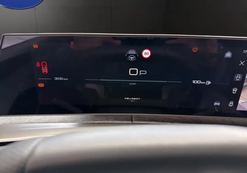 Affichage numérique du tableau de bord du Peugeot 5008 hybride, avec vitesse, alertes et autonomie visible.