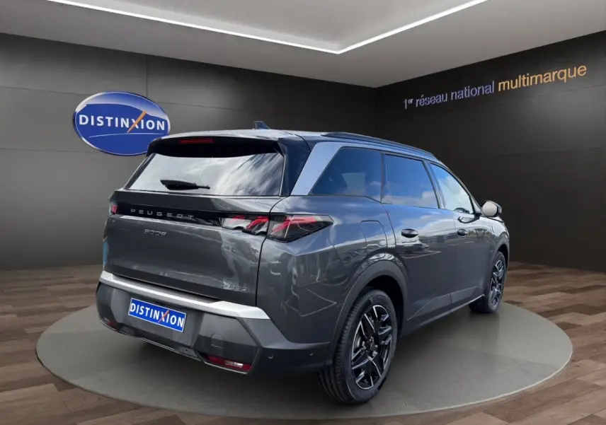 Vue 3/4 arrière droite d’un Peugeot 5008 gris foncé hybride avec jantes noires et feux LED caractéristiques.
