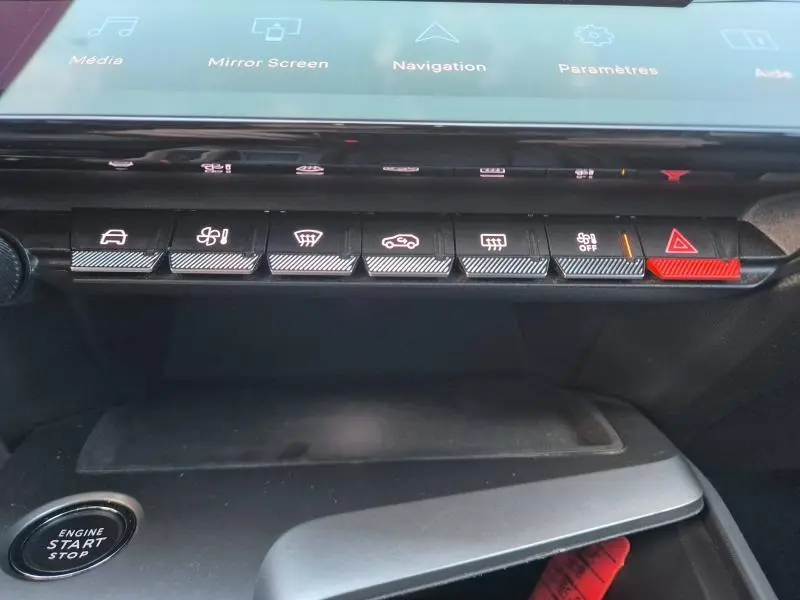 Vue rapprochée des commandes centrales avec boutons fonctionnels et bouton rouge de signalisation dans un Peugeot 308 2023.