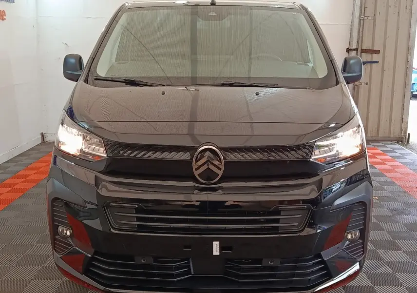 Vue frontale d’un Citroën Jumpy XL noir 2025 avec phares allumés dans un garage intérieur.