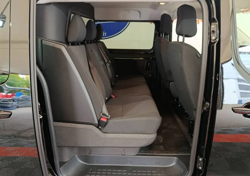 Vue latérale intérieure côté droit du Citroën Jumpy XL noir, montrant la banquette arrière trois places en tissu gris.