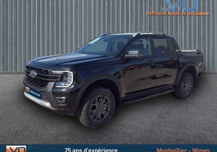 Ford Ranger Wildtrak noir en 3/4 avant droit, avec barres de toit, marchepieds et jantes alliage 18 pouces.
