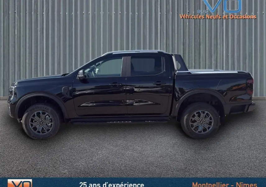 Vue de profil côté gauche du Ford Ranger Wildtrak noir 2025 avec jantes alliage 18 pouces et barres de toit.
