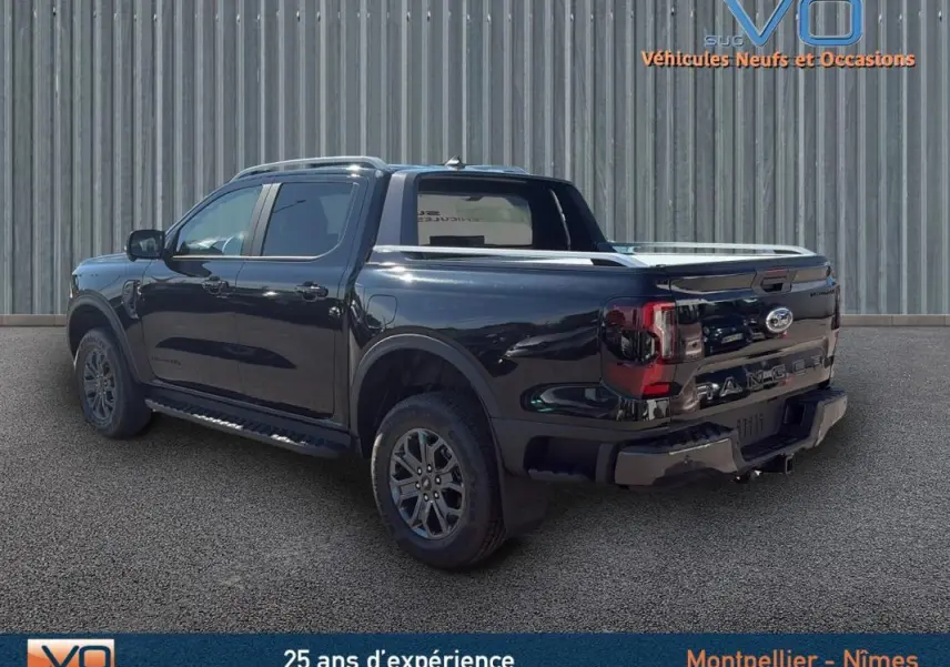 Ford Ranger Wildtrak noir vu en 3/4 arrière droit, avec barres de toit, marchepieds et vitres surteintées.