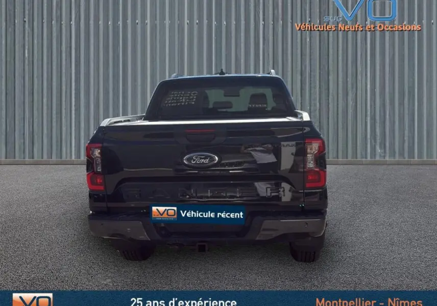 Vue arrière d'un Ford Ranger noir 2025 avec barres de toit et marchepieds visibles sur un sol gris.