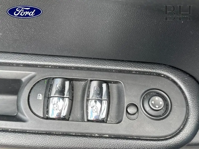 Gros plan sur les commandes de lève-vitres chromées côté conducteur d'une MINI Countryman Chili Red, intérieur noir.
