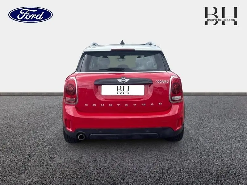 Vue arrière d'une MINI Countryman Chili Red avec toit blanc et sortie d'échappement chromée visible.