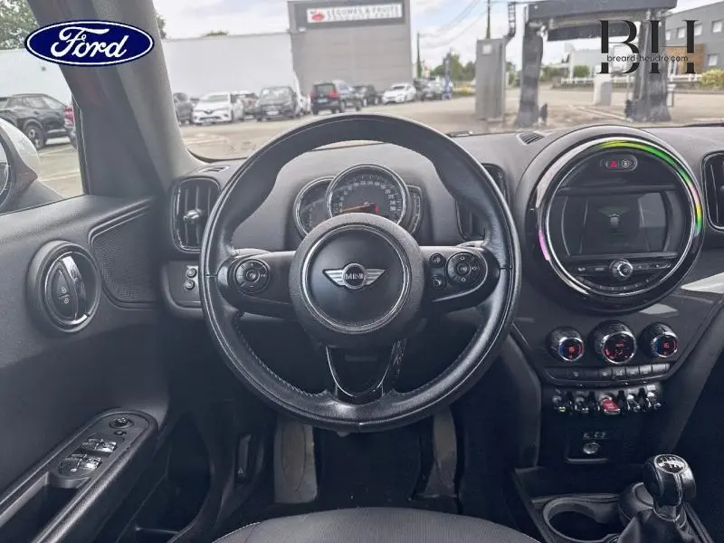 Vue intérieure centrée sur le volant cuir multifonction d'une MINI Countryman Chili Red de 2018 avec tableau de bord et console.