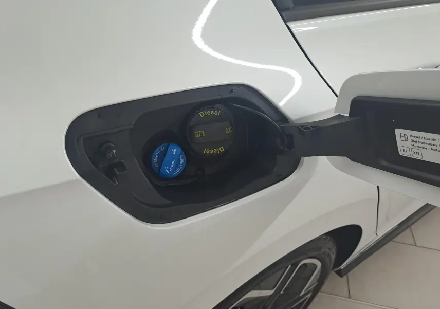Gros plan sur la trappe à carburant côté gauche d'une Volkswagen Golf blanche nacrée avec bouchons Diesel et AdBlue visibles.
