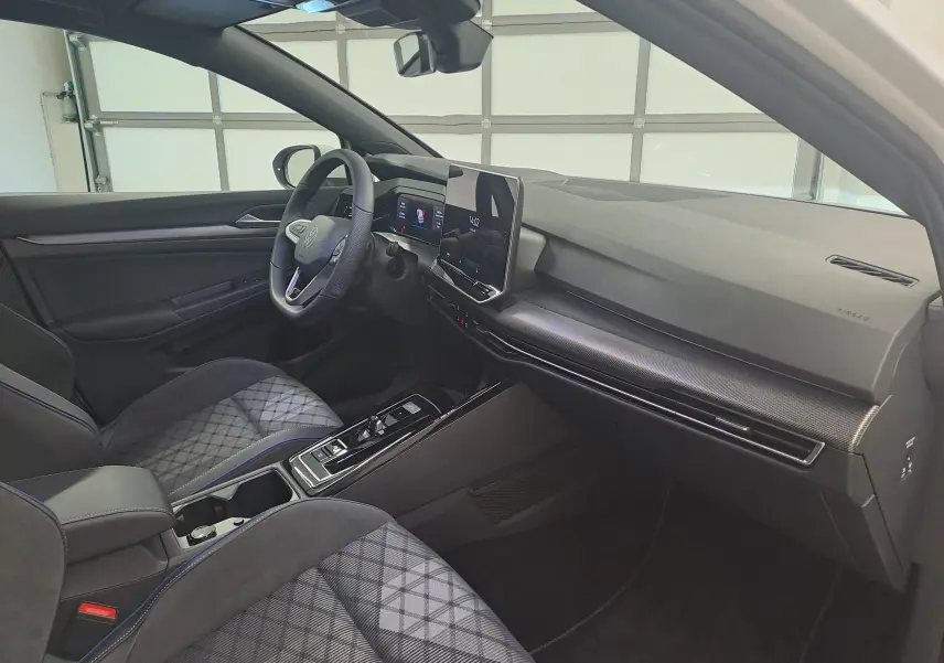 Vue intérieure côté conducteur de la Volkswagen Golf 2.0 TDI 2025 avec sièges tissu à motif et tableau de bord moderne.