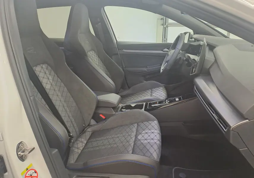 Vue intérieure côté conducteur de la Volkswagen Golf 2.0 TDI blanche, sièges sport en tissu et alcantara avec surpiqûres bleues.