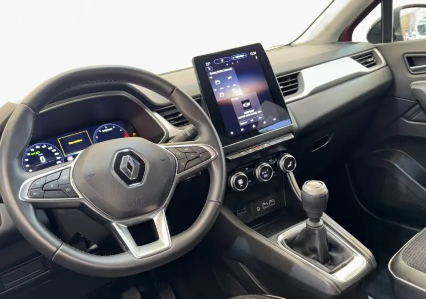 Vue intérieure du tableau de bord et volant du Renault Captur rouge 2024 avec écran tactile vertical et boîte manuelle.