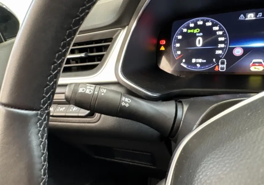 Gros plan intérieur sur le combiné d'instruments numérique et le volant noir du Renault Captur 2024 essence.