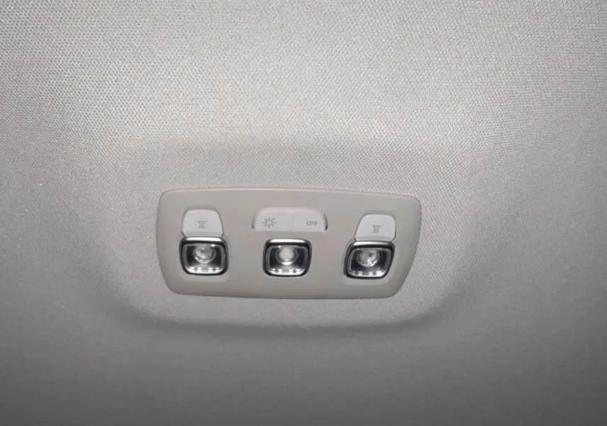 Plafonnier intérieur gris avec trois boutons lumineux dans un Renault Captur rouge vue de dessous.
