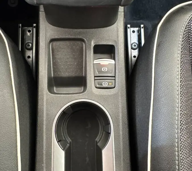 Vue plongeante sur la console centrale noire du Renault Captur rouge 2024, avec frein à main électrique et porte-gobelets.