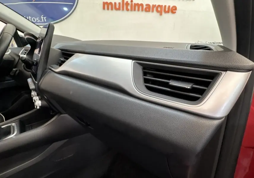 Intérieur côté passager du Renault Captur rouge 2024, tableau de bord moderne avec écran tactile vertical et boîte manuelle.