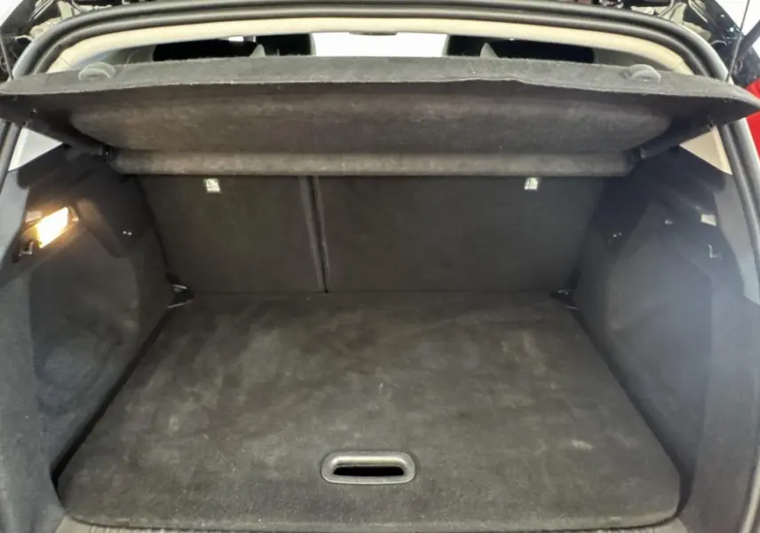 Coffre ouvert vu de l'arrière d'un Renault Captur rouge 2024, espace de chargement vide et tapis noir.