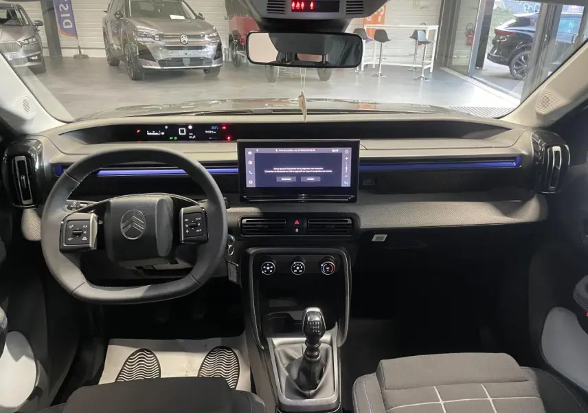 Vue intérieure avant du tableau de bord et volant de la Citroën C3 gris foncé avec écran tactile central et boîte manuelle.
