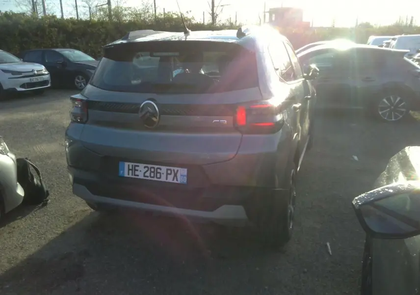 Vue arrière d'une Citroën C3 gris foncé 2025 avec barres de toit noir brillant, stationnée en extérieur au soleil.