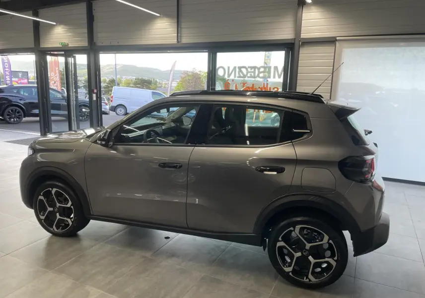 Vue de profil côté gauche d'une Citroën C3 2025 gris foncé avec jantes 17 pouces et barres de toit noir brillant.