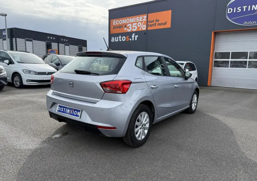 Vue 3/4 arrière droite d'une SEAT Ibiza 2022 argent Urban avec jantes alliage 15 pouces sur parking extérieur.