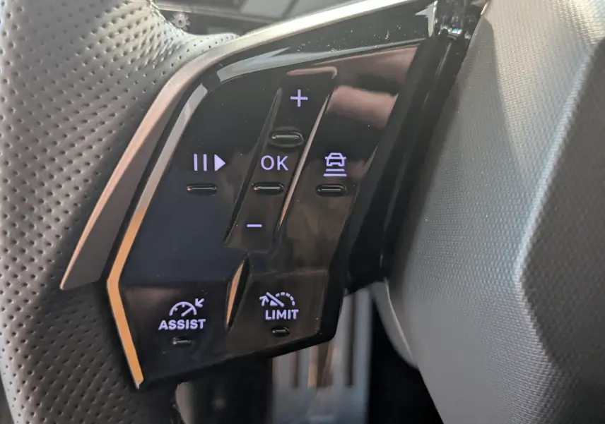 Gros plan sur les commandes au volant du Peugeot 3008 Hybrid 145 GT, boutons noirs avec éclairage blanc.
