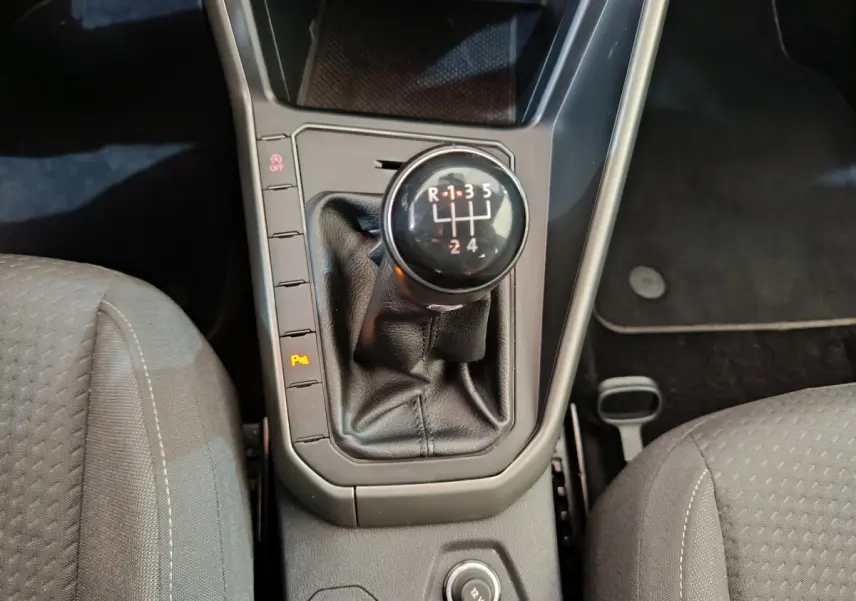 Le levier de vitesses manuel noir de la Volkswagen Polo 2020, vu de dessus entre les sièges avant gris.