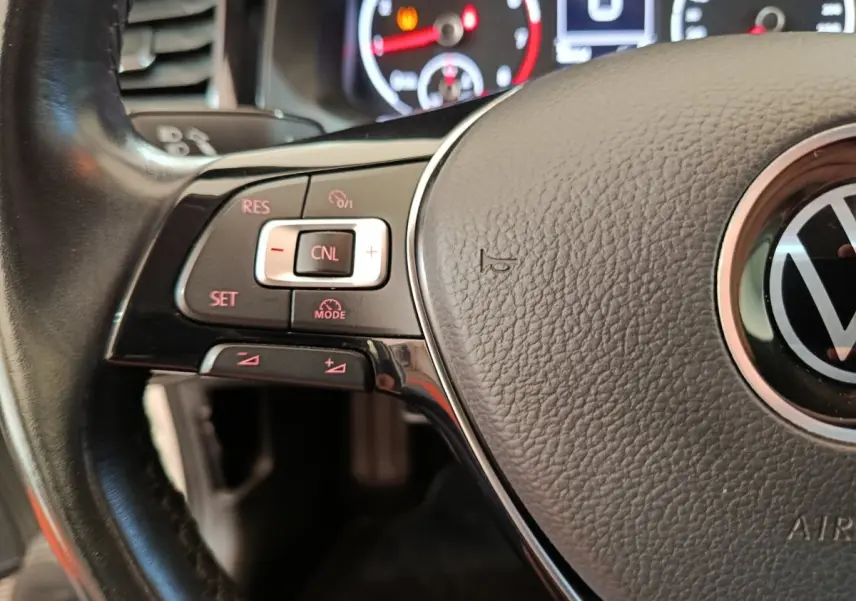 Gros plan sur le volant cuir noir de la Volkswagen Polo 2020 avec commandes de régulateur de vitesse et logo VW central.