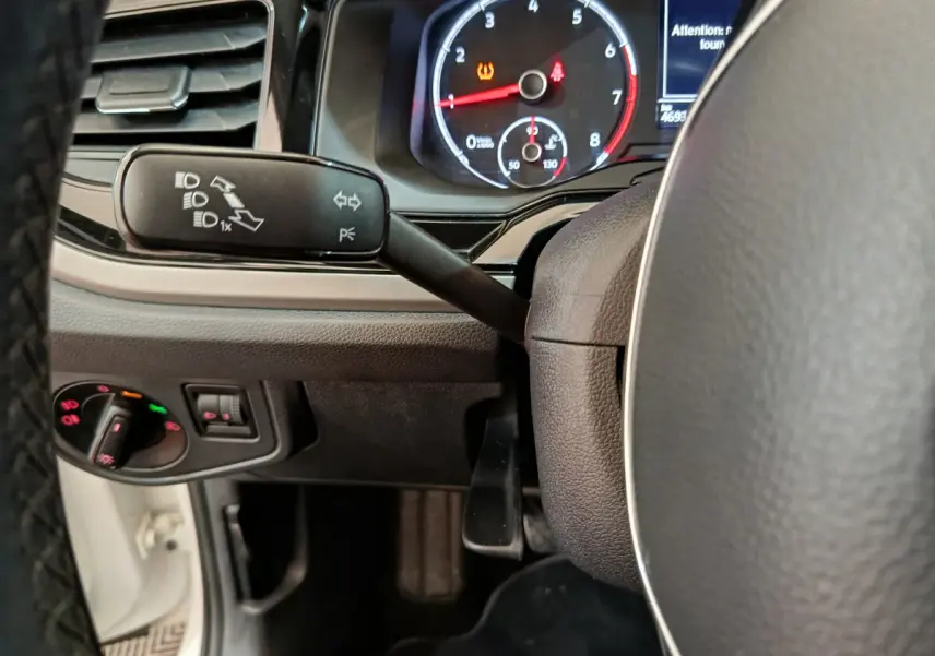 Gros plan sur le tableau de bord et le volant de la Volkswagen Polo blanche, avec indicateurs et commandes visibles.