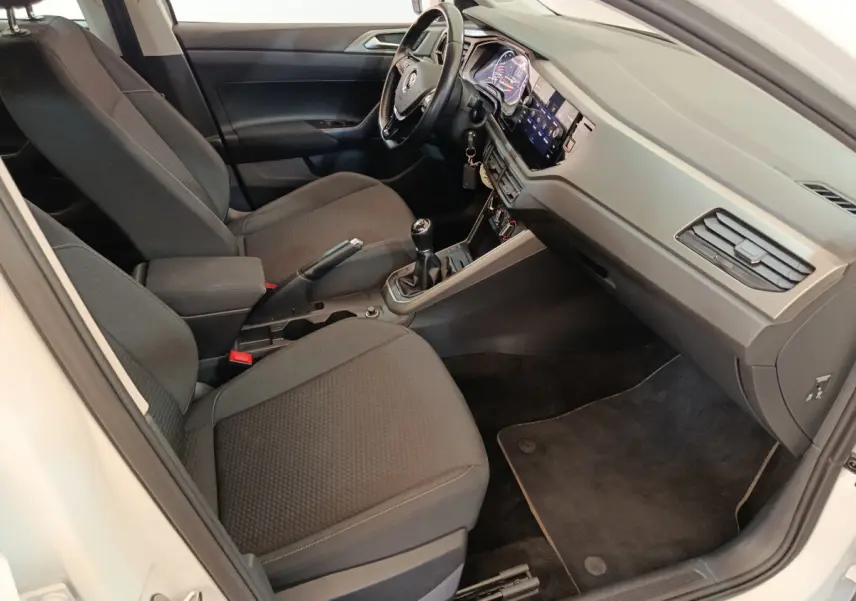 Intérieur de la Volkswagen Polo blanche 2020, vue côté conducteur, tableau de bord moderne avec écran tactile et volant cuir.