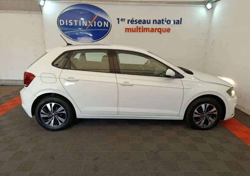 Profil droit d'une Volkswagen Polo blanche 2020 avec jantes alliage et feux avant allumés en intérieur showroom