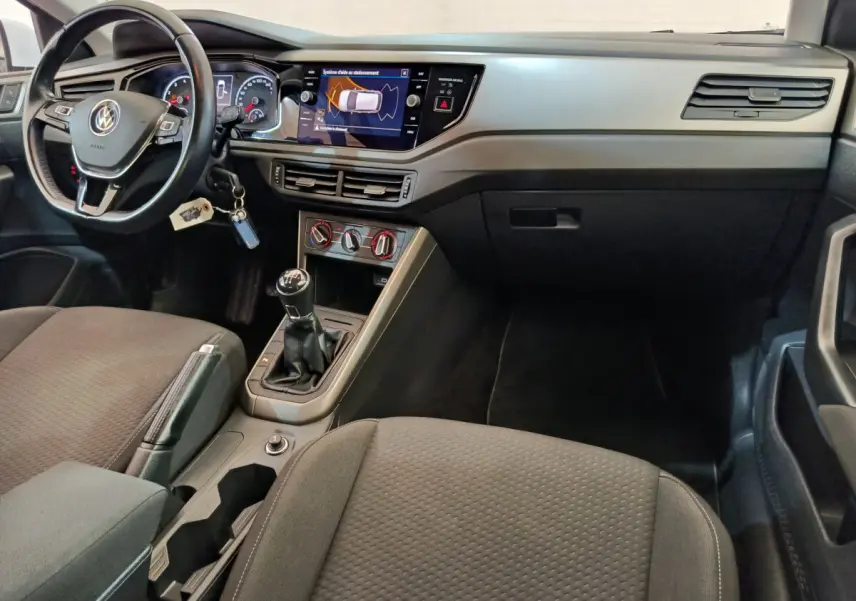Intérieur de Volkswagen Polo 2020 essence, vue du poste de conduite avec volant cuir, boîte manuelle et écran tactile central.