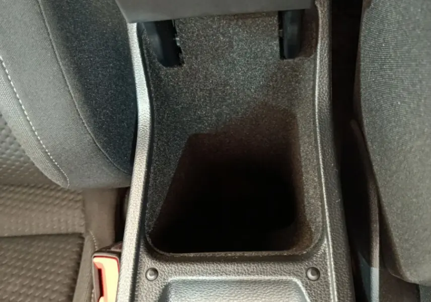 Vue rapprochée de la console centrale ouverte avec rangement noir entre les sièges avant d'une Volkswagen Polo blanche 2020.