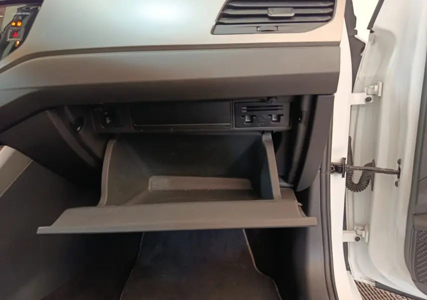 Gros plan sur la boîte à gants ouverte côté passager d'une Volkswagen Polo blanche, intérieur noir et gris.