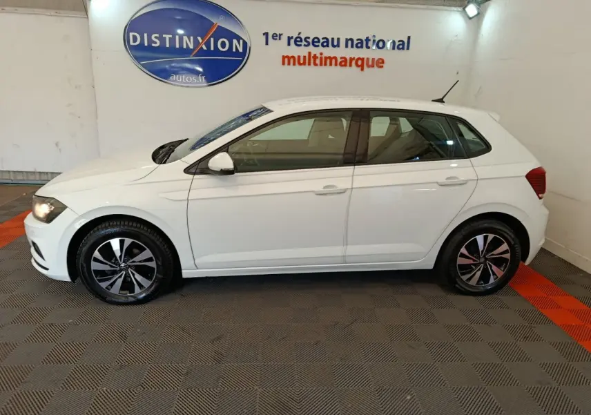 Profil côté gauche d'une Volkswagen Polo blanche 2020 en intérieur, avec jantes alliage et feux arrière visibles.