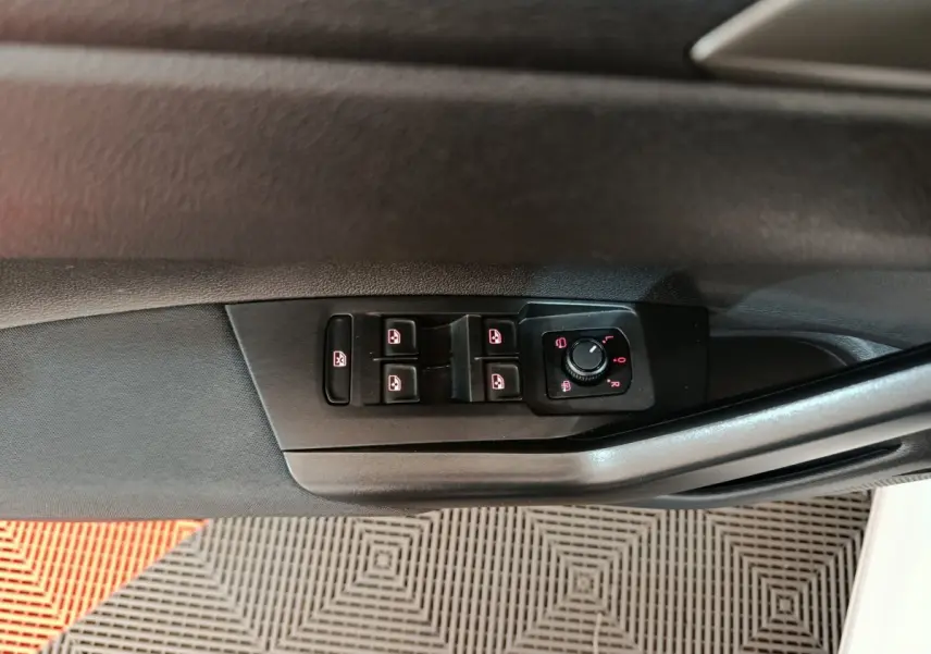 Gros plan sur les commandes de lève-vitres et rétroviseurs sur la porte côté conducteur d'une Volkswagen Polo blanche.