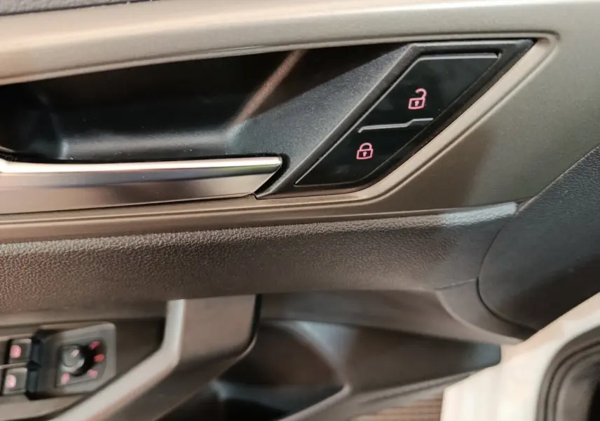 Poignée intérieure côté conducteur de Volkswagen Polo blanche, avec boutons de verrouillage éclairés en rouge.