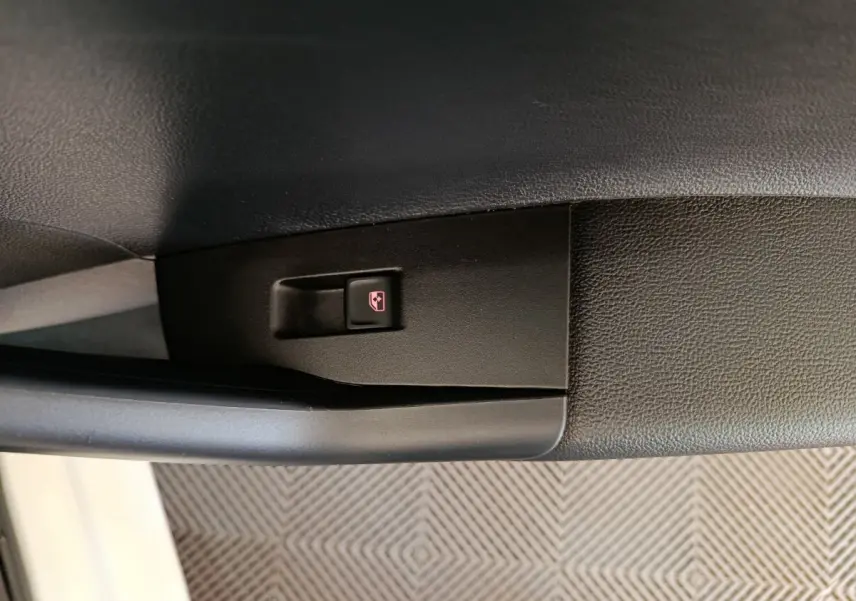 Gros plan sur le bouton de verrouillage centralisé noir dans la portière côté conducteur d'une Volkswagen Polo blanche 2020.