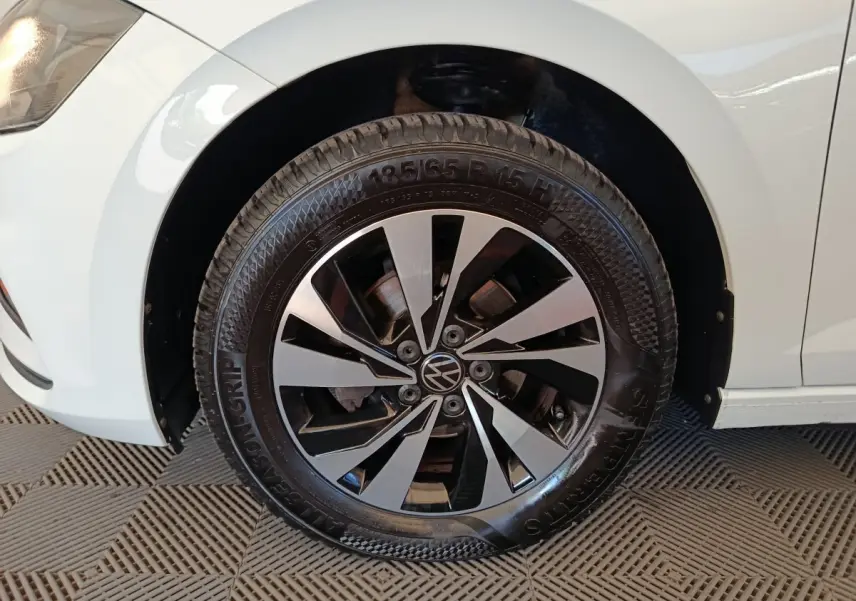 Gros plan sur la roue avant gauche d'une Volkswagen Polo blanche, avec jante alliage bicolore et logo VW central.