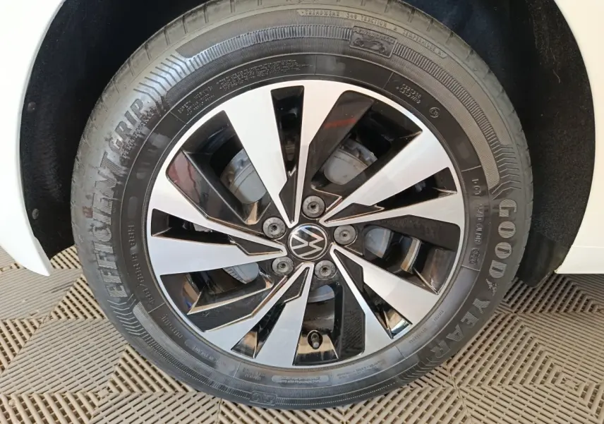 Gros plan sur la roue avant droite d'une Volkswagen Polo blanche avec jante alliage bicolore noir et argentée.